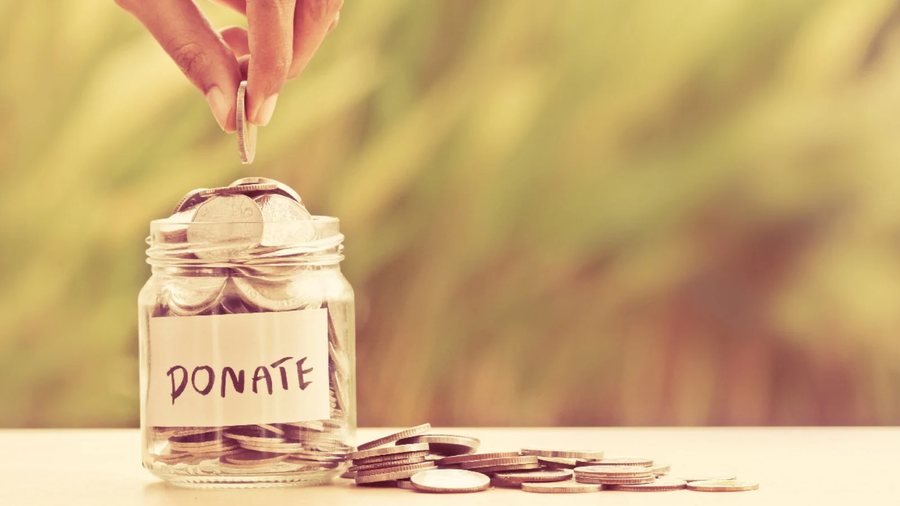 A hand dropping a coin into a jar labelled Donate